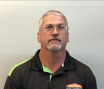 Headshot of man wearing glasses and SERVPRO uniform in front of gray background