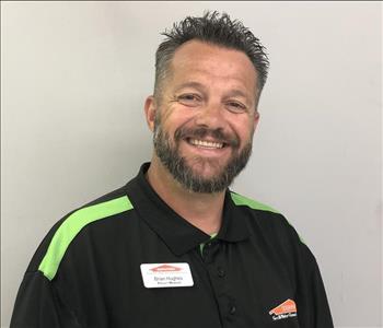 Headshot of smiling man wearing SERVPRO uniform in front of gray background