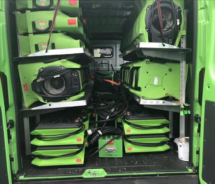 Green equipment stored in rows inside the back of a vehicle