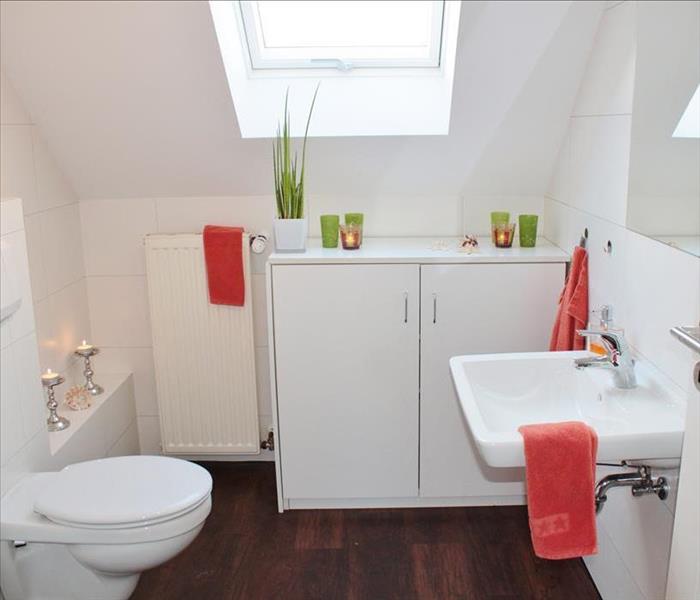 Wood-floor bathroom with white toilet, sink, and walls