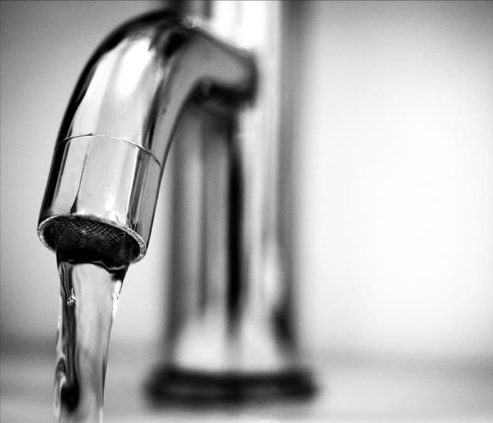 Close-up photo of sink faucet pouring water