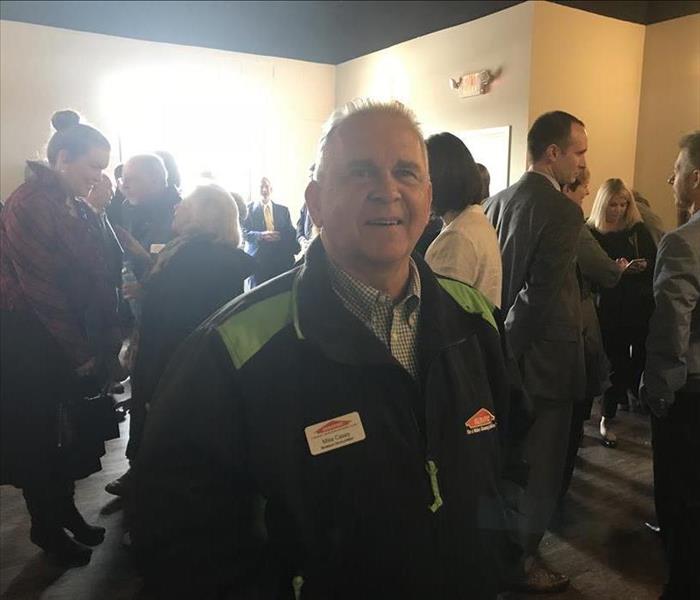Man in SERVPRO jacket standing in a crowd of people